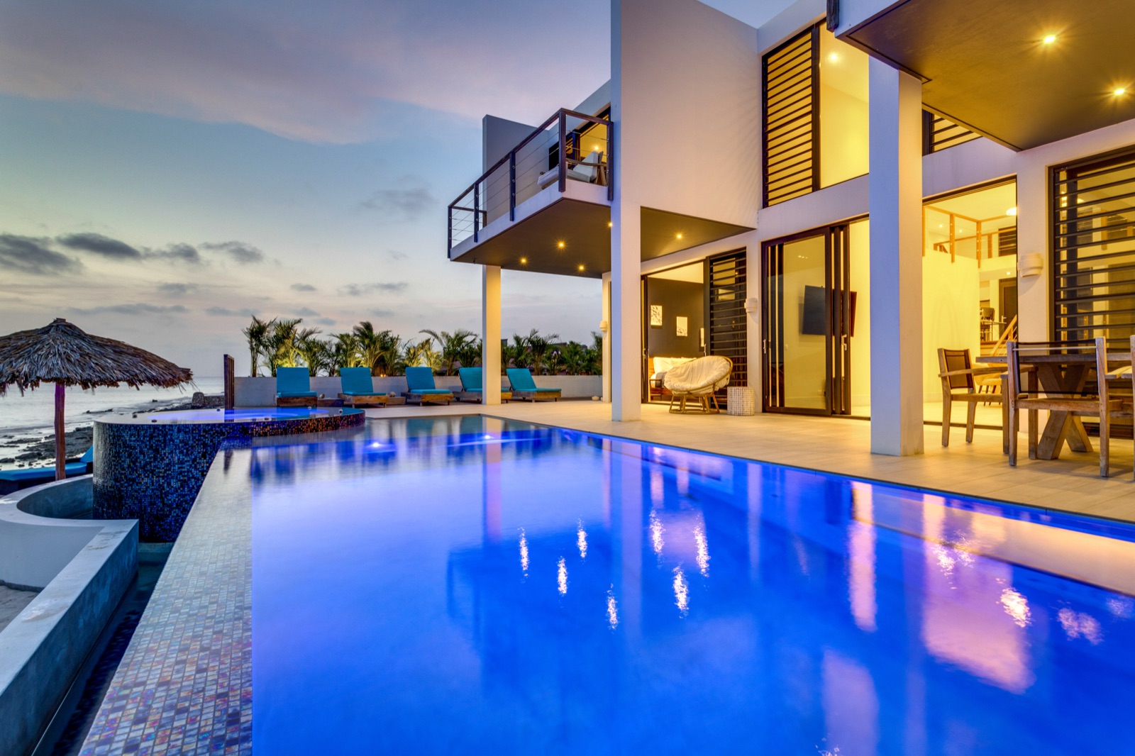 Beach Villa 3 with its illuminated private pool and oceanfront terrace at dusk